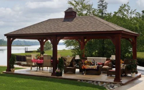 Elegant wooden gazebo with outdoor furniture in a lush garden.